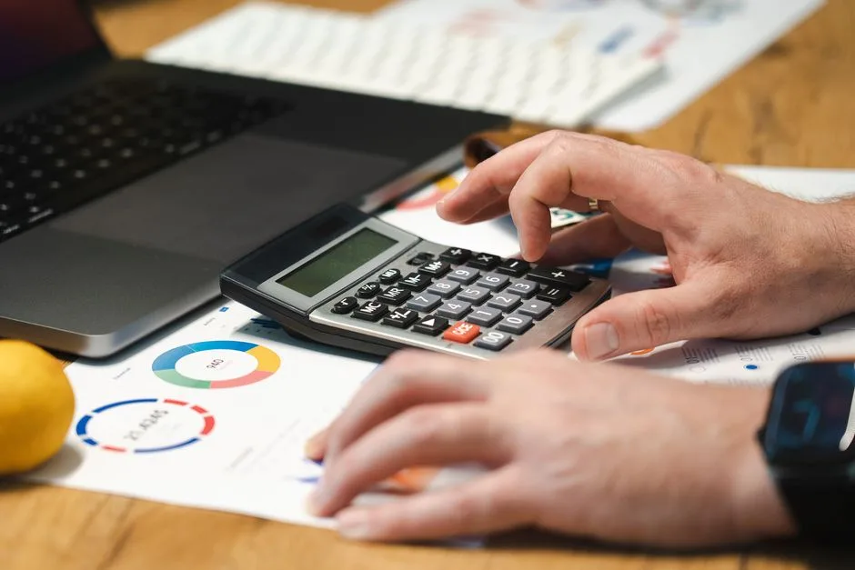 Mains sur le clavier d’un ordinateur portable, documents comptables à côté
