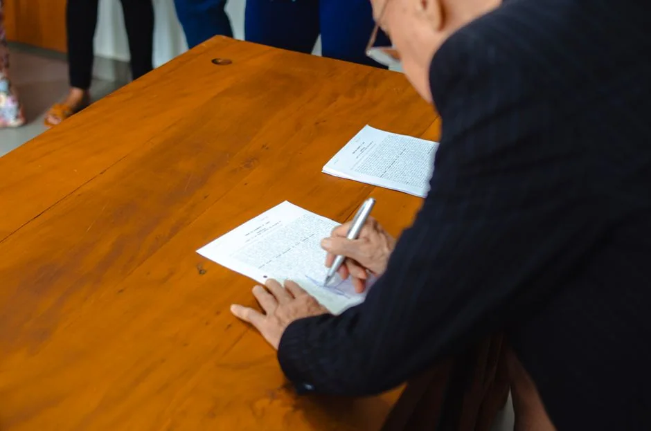Mains d’une dirigeante signant des documents posés sur une table en bois
