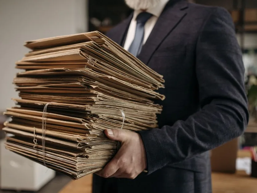 Dirigeant de TPE portant les dossiers de sa comptabilité dans son bureau